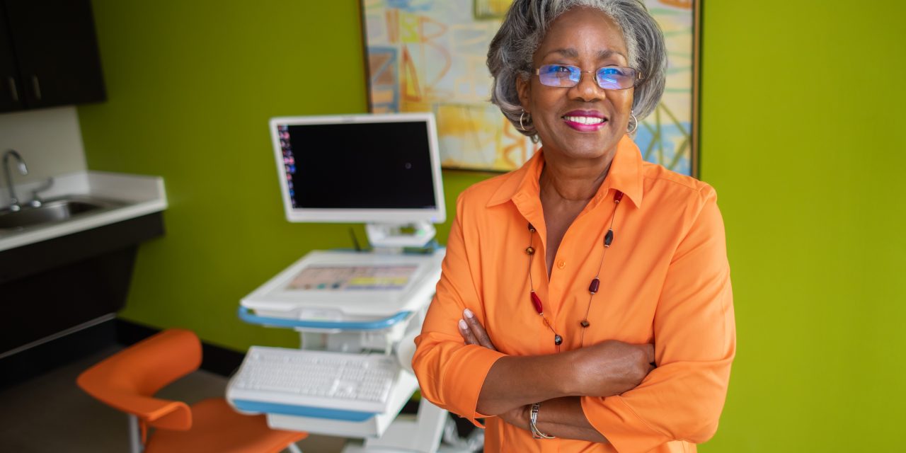 Image of smiling woman with gray hair and orange shirt.